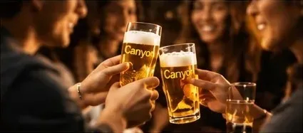 Friends clinking pint glasses engraved with the Canyon logo.